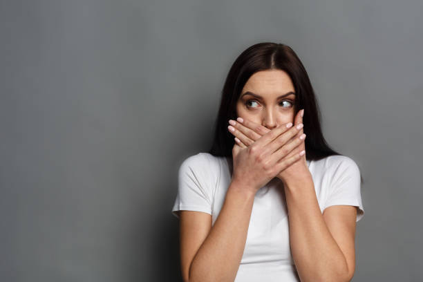 woman covering mouth with both hands looking to her left.