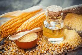 image showing two ears of corn on a table. This is accompanied by a small bottle of corn syrup.